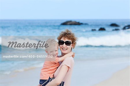 laughing mother holding her son at the beach