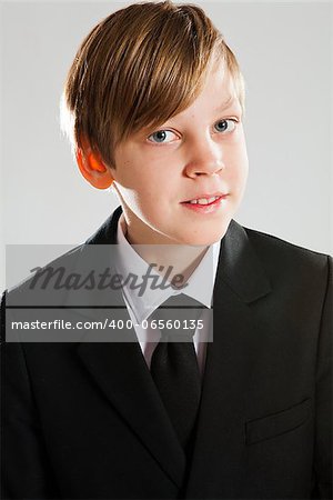 Studio portrait of a happy smiling young boy wearing black suit