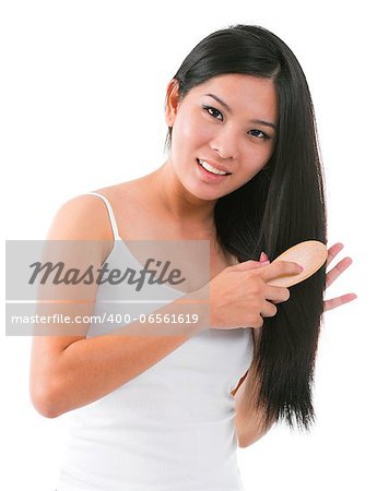 Young Asian girl combing hair over white background