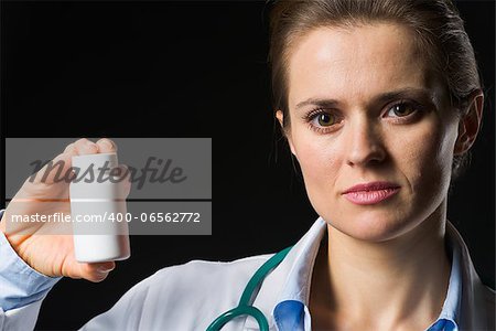 Medical doctor woman showing medicine bottle on black background