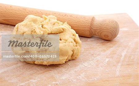 Wooden rolling pin and a fresh ball of pastry ready to be rolled out on a floured board