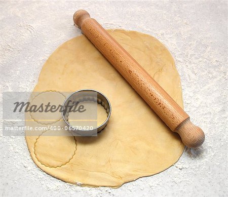 Rolling pin and cutter on fresh pastry, cutting out circles on a floured surface