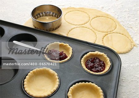 Cutting and filling pastry shapes to make jam tarts