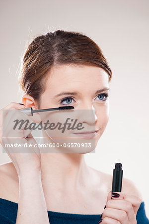 Head and Shoulders Portrait of Teenage Girl Putting on Mascara in Studio