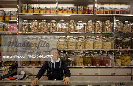 Man standing behind counter of a grocery shop, looking at camera, Hong Kong, China, Asia