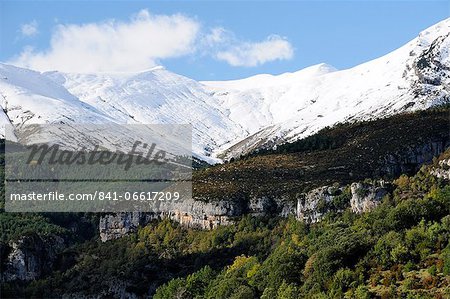 Limestone escarpments above Escuain gorge with snow covered high Pyrenees peaks in the background, Huesca, Aragon, Spain, Europe