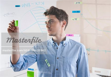 Young Man Working in an Office, Looking Through Glass Board, Germany