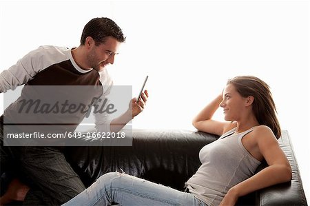 Man taking picture of girlfriend on sofa