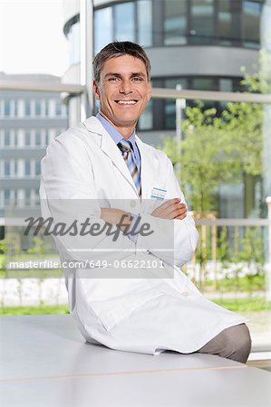 Doctor sitting on desk in office