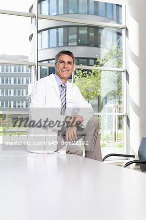 Doctor sitting on desk in meeting room