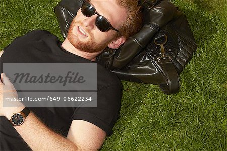 Man laying on bag in grass