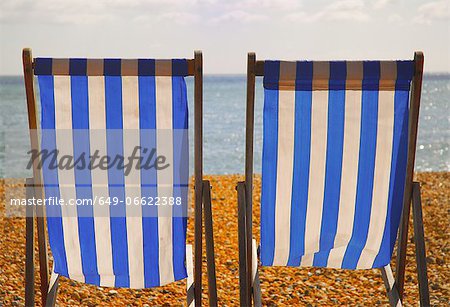 Empty lawn chairs on rocky beach