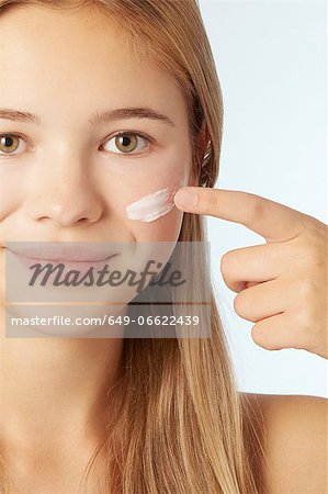 Teenage girl moisturizing her face
