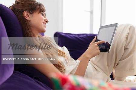 Woman using tablet computer on sofa