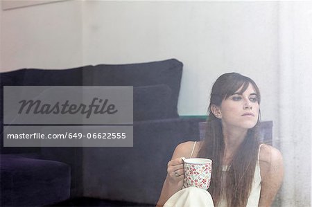 Woman having cup of coffee at window