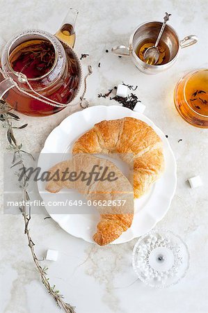 Croissants, honey and tea on table