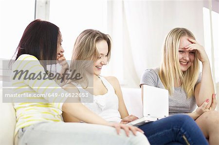 Teenage girls using laptop on sofa