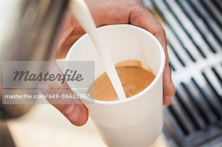Close up of milk pouring into coffee cup Close up of milk pouring into coffee cup