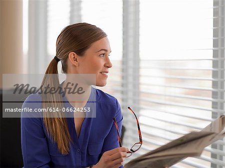 Businesswoman reading newspaper on sofa