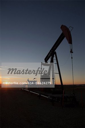 Silhouette of oil well in dry landscape
