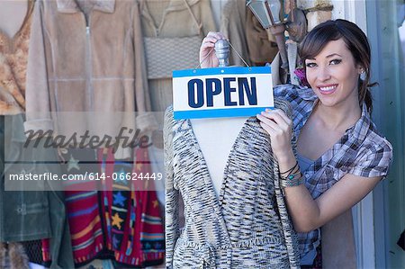 Woman hanging open sign on mannequin