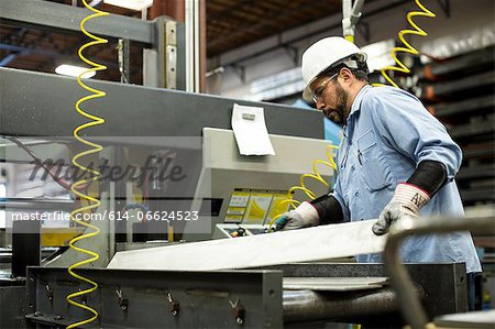 Worker using machinery in metal plant