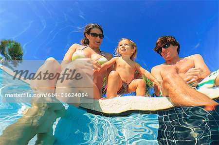 Family relaxing by swimming pool