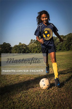 Girl playing soccer in field