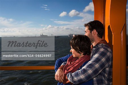 Couple hugging on ferry in urban harbor