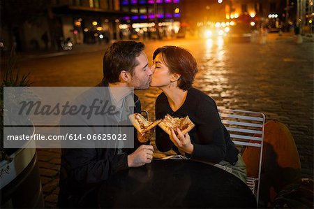 Kissing couple having pizza outdoors