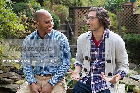 Smiling men talking in backyard