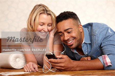 Couple listening to headphones on bed