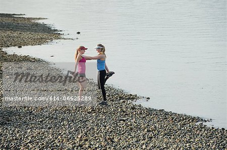 Teenage girls stretching on rocky beach