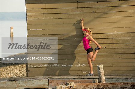Teenage girl stretching on rocky beach