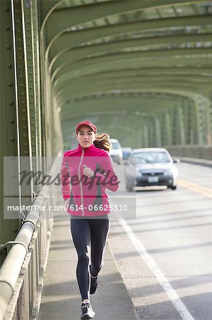 Woman running on urban bridge