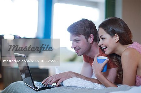 Couple using laptop together on bed