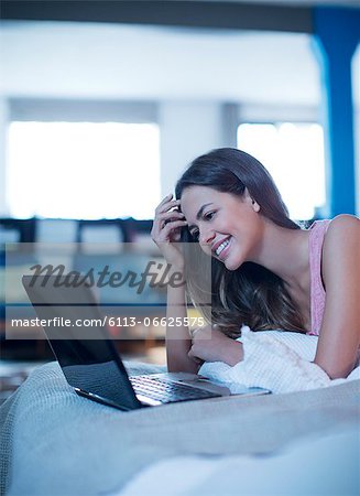 Woman using laptop on bed