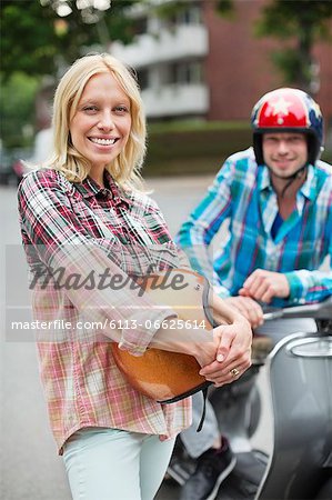 Smiling woman holding scooter helmet