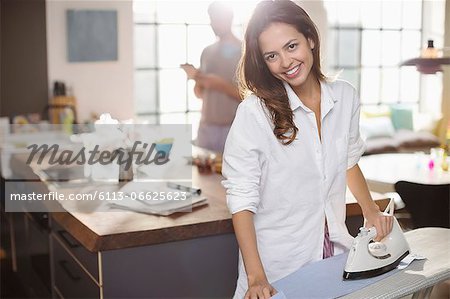 Smiling woman ironing in kitchen