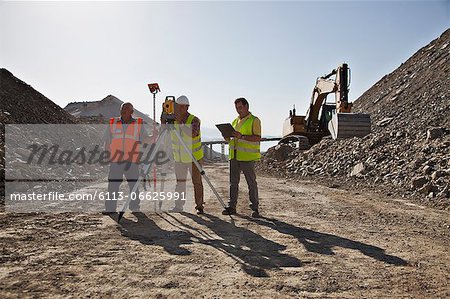 Workers using leveling machinery in quarry