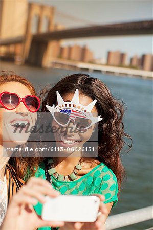 Women in novelty sunglasses taking picture by city cityscape