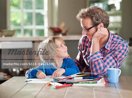 Father and son doing homework at kitchen table