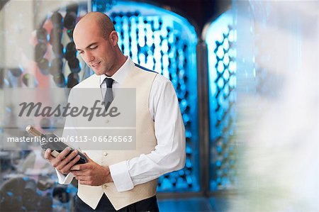 Waiter reading bottle of wine in kitchen