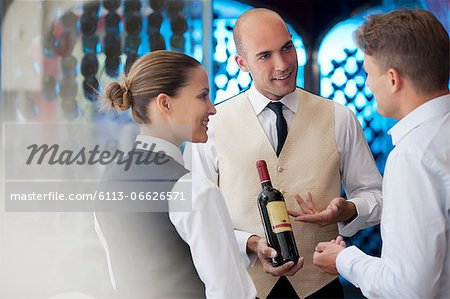 Waiters discussing bottle of wine in restaurant