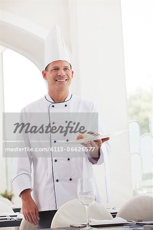 Chef holding plate of food in restaurant