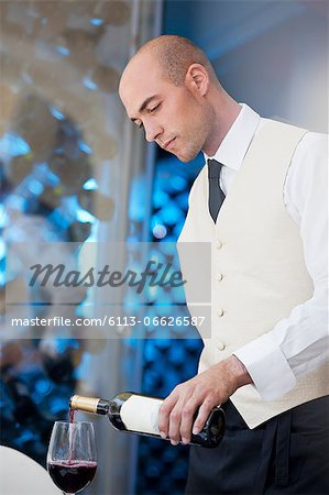 Waiter pouring glass of wine in restaurant