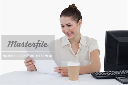 Happy businesswoman looking a document against a white background