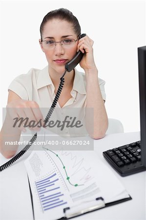 Portrait of a manager making a phone call while looking at statistics against a white background