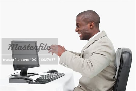 Angry businessman using a monitor against a white background