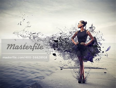 Elegant black girl with a black dress with black paint standing on a pier